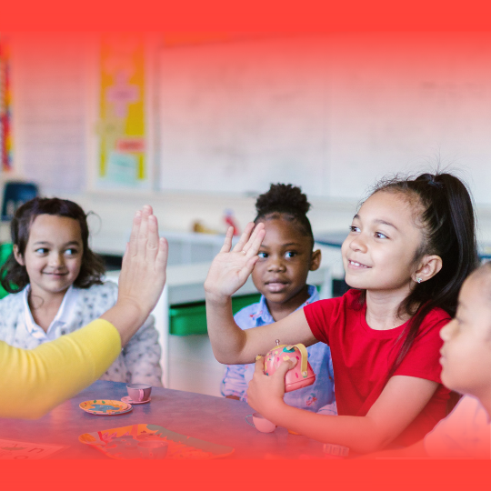 Children in classroom receiving a high-five from teacher.